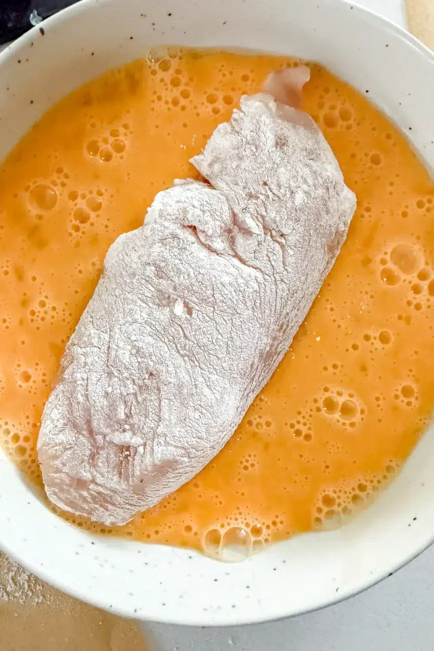 Flour coated chicken dipped into beaten egg