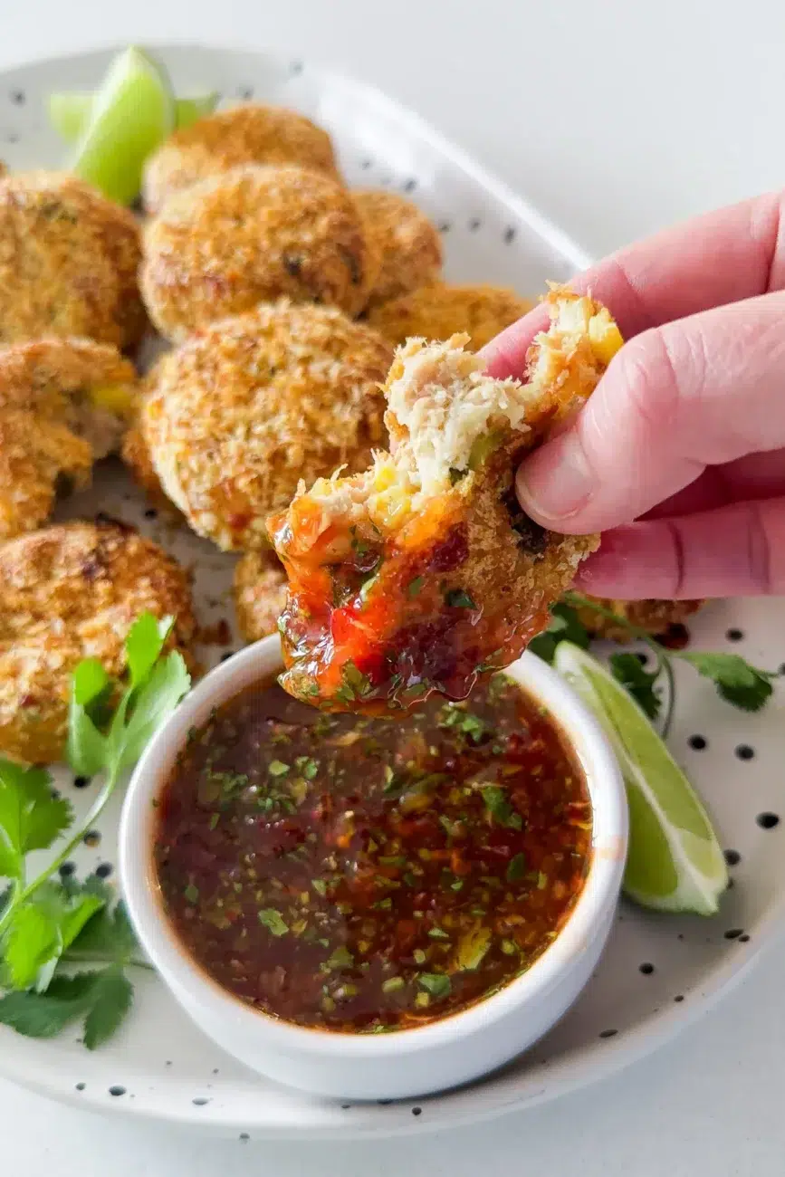 Half a fish cake being dipped into sweet chilli lime sauce