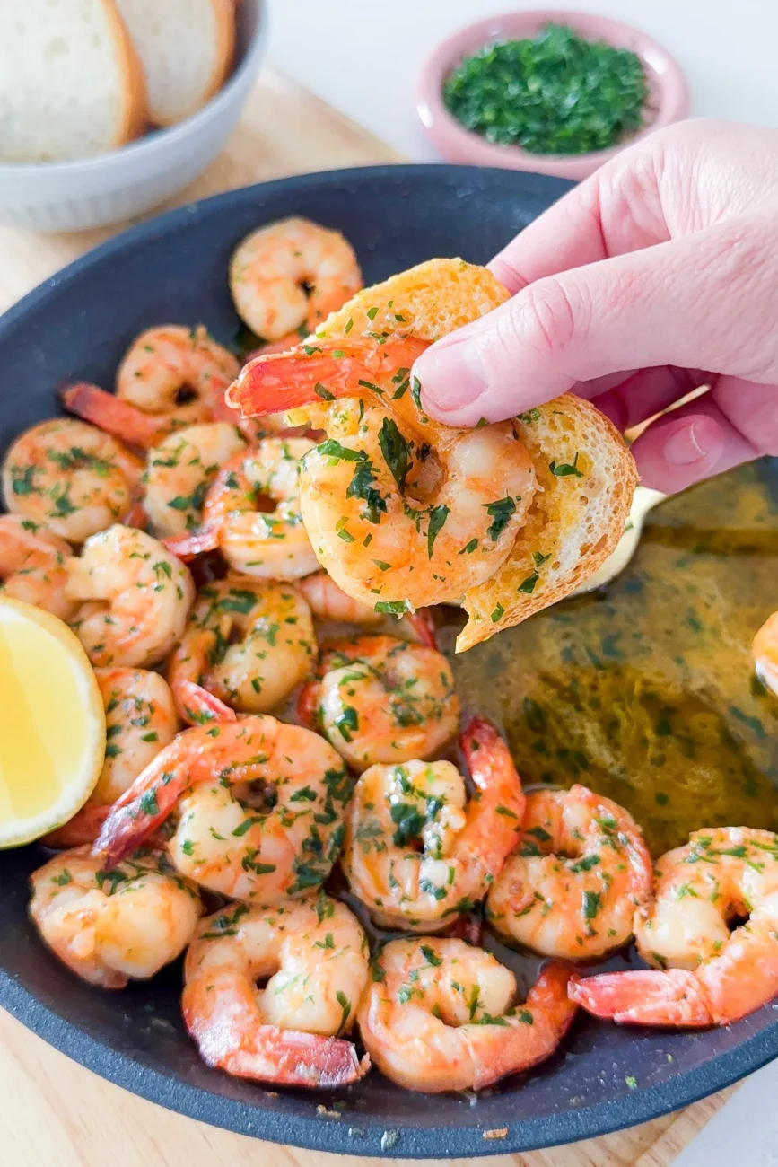 bread being dipped into delicious buttery mixture coating prawns